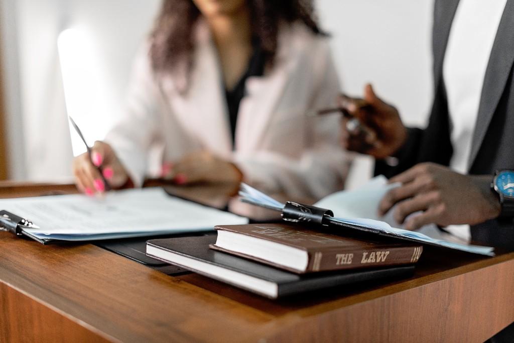 Legal professionals reviewing documents beside a book titled The Law on a polished wooden desk